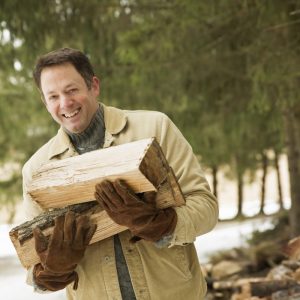 A man collecting firewood, logs for the fire, in snow in winter.