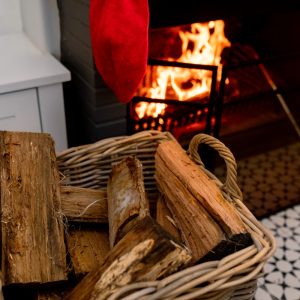 Logs of wood in basket lying at fireplace wit christmas sock. christmas, festivity and tradition at home.